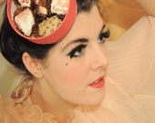 A cerise pink round 'Chocolate box' fascinator hat, hand printed and beaded using vintage fabrics.
