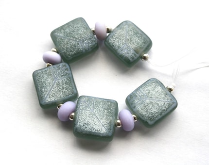 5 Grey lampwork tile beads with a scattering of white enamels and fine stringer pattern in pale lilac accompanied by 4 pale lilac spacer beads