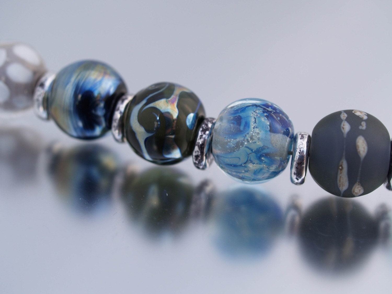 eight handmade glass beads in icy shades of blue and grey