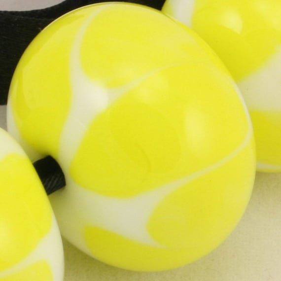 A set of 7 lampwork glass beads in bright yellow and white.