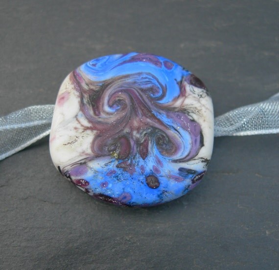 A hand-shaped flat tab focal of swirling blues and purple on a pale grey background. Etched to give a matte softness.