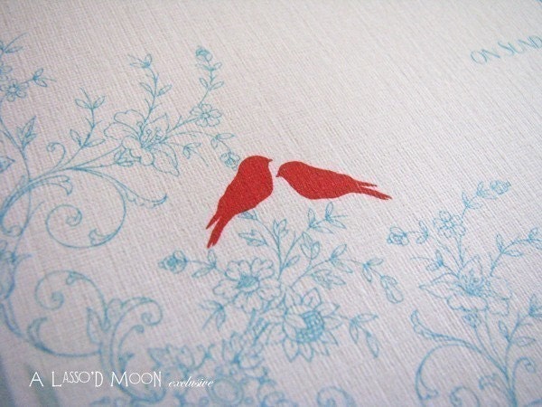 Shown in pale blue with red love birds and floral accents this invitation 