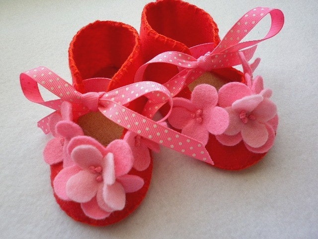 Red baby booties with flamingo pink flowers.