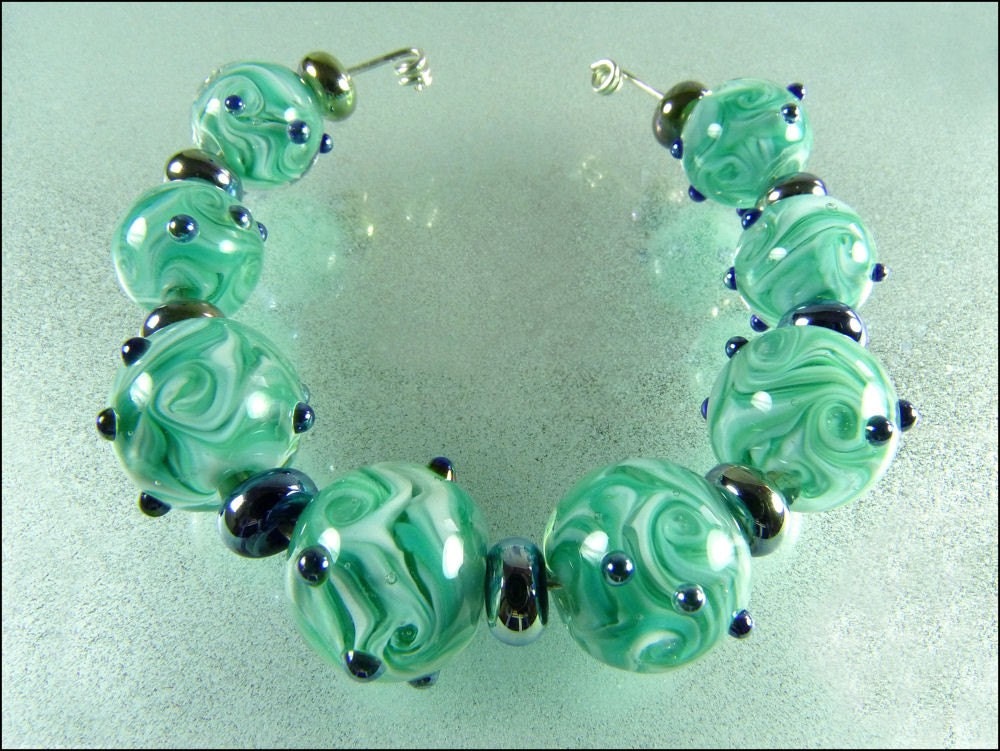 The round beads are a swirly mixture of teals and white encased with crystal clear glass