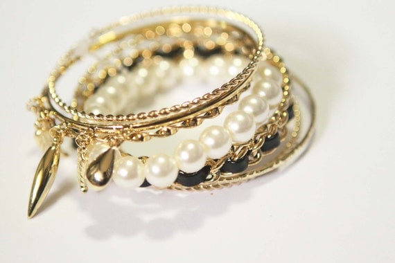 WRAPPED. 7 piece bangle set of mix pearl and gold pieces with charms