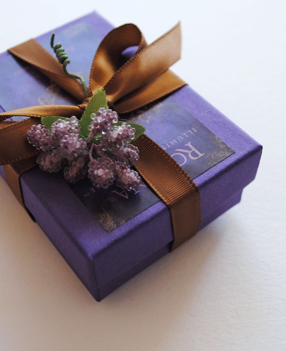 purple box gift wrapped fragrance with brown ribbon and flowers