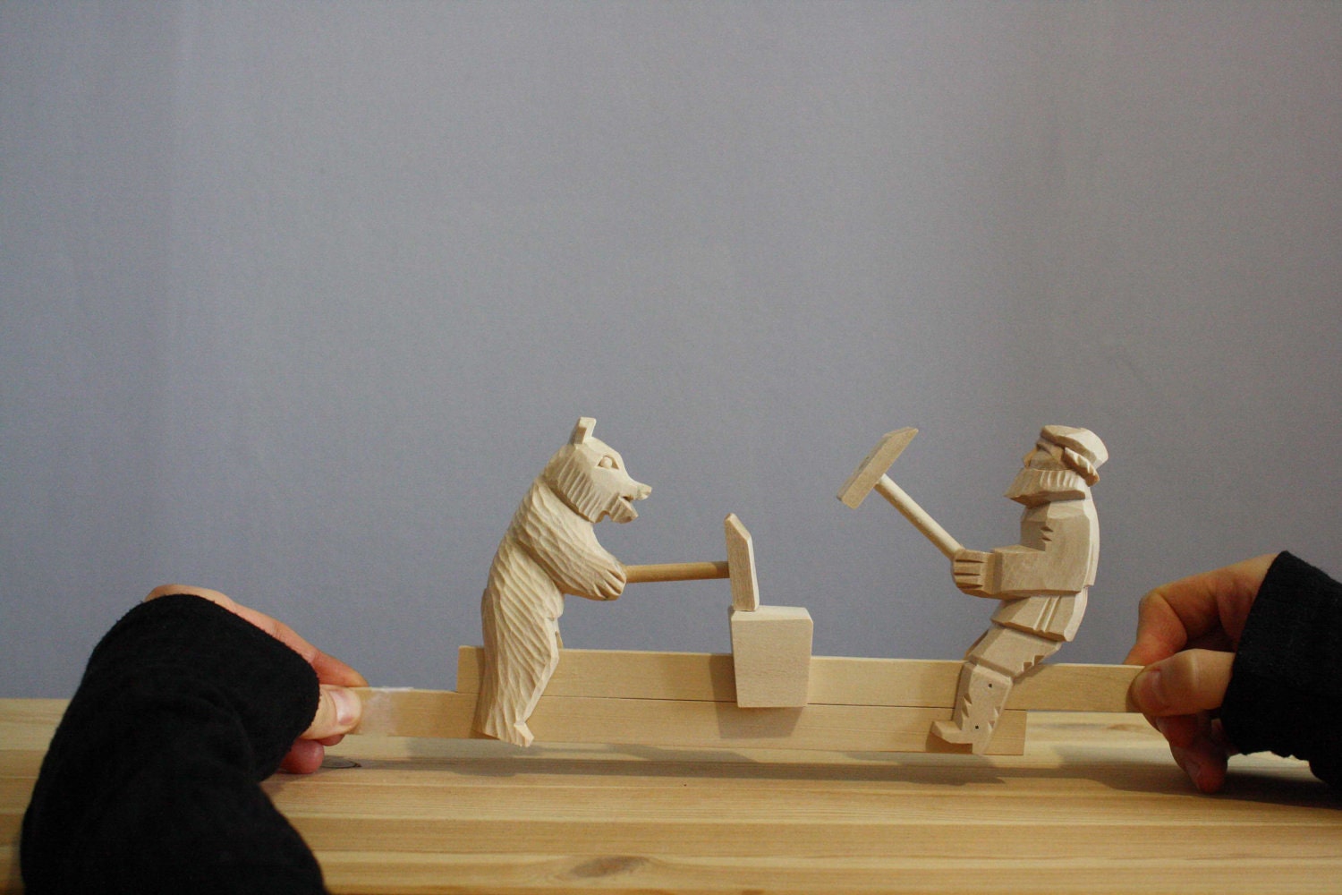 wooden carved moving bear and man beaten with a hammer